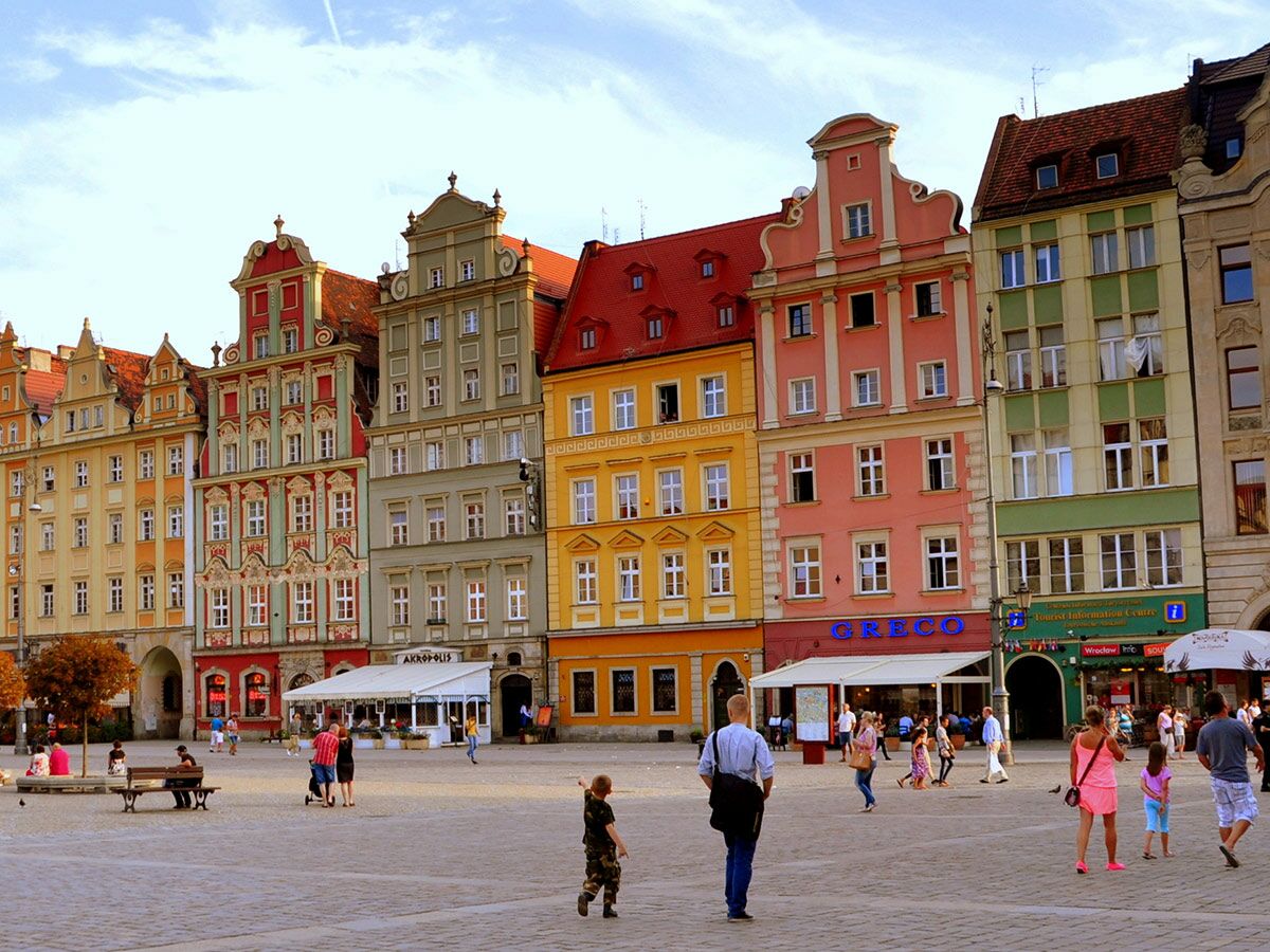 Historischer Marktplatz Wroclaw mit bunten Bürgerhäusern und vielen Menschen, die den sonnigen Tag genießen.