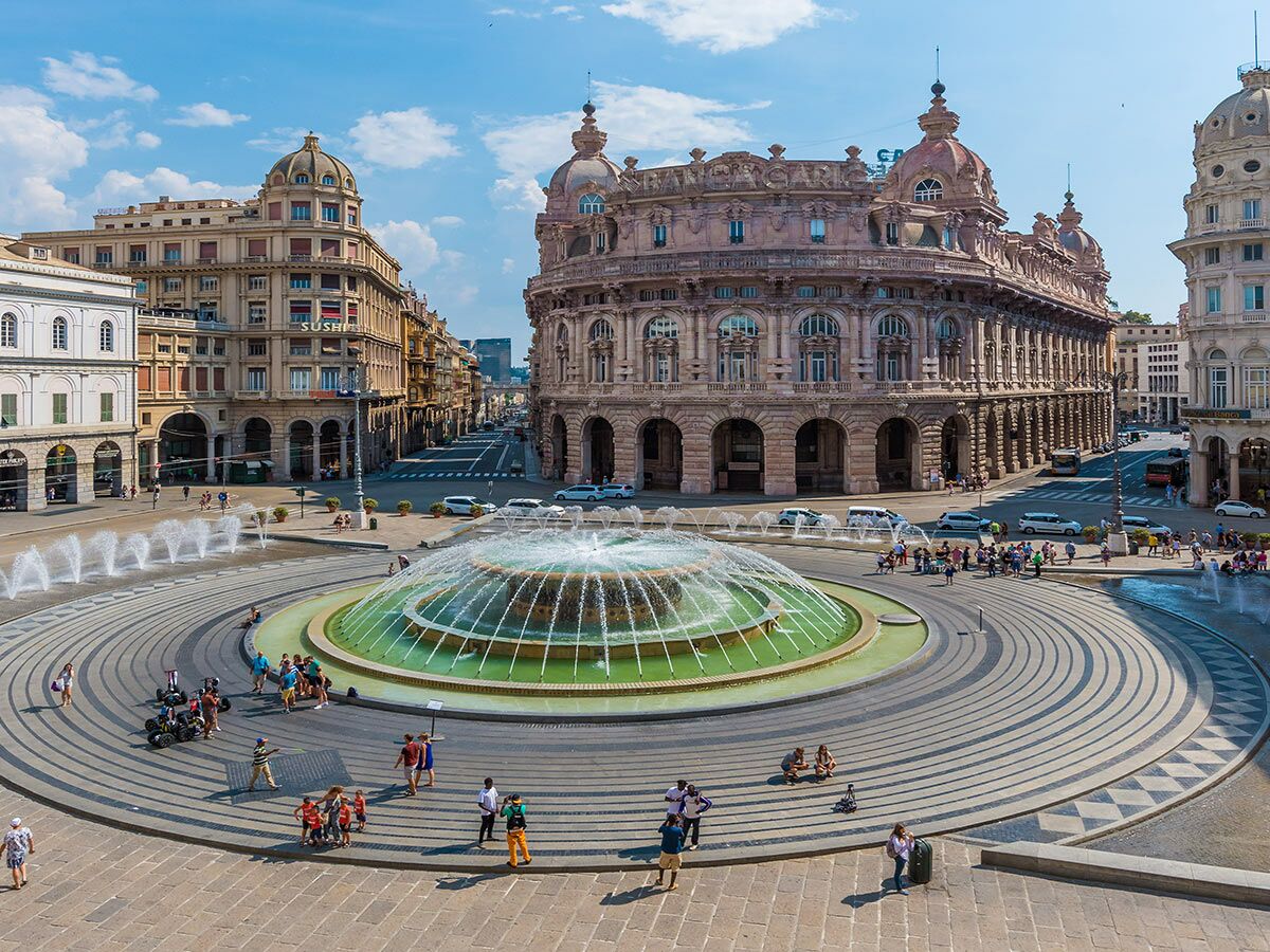 Panoramablick auf Genua, Piazza De Ferrari. Großer Brunnen, historische Gebäude, belebte Menschenmengen unter blauem Himmel.