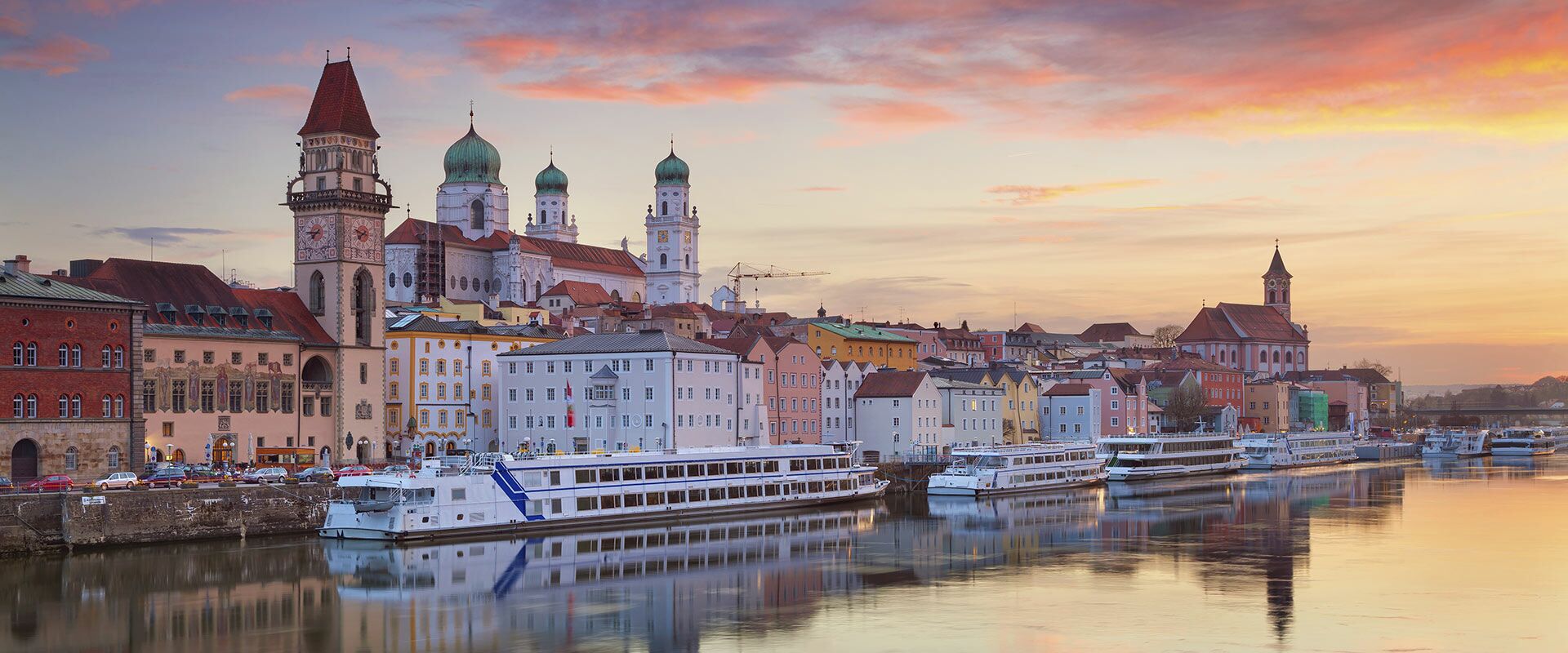 Panoramablick auf die Passauer Altstadt bei Sonnenuntergang mit St. Stephansdom, Rathaus und Schiffen auf der Donau.