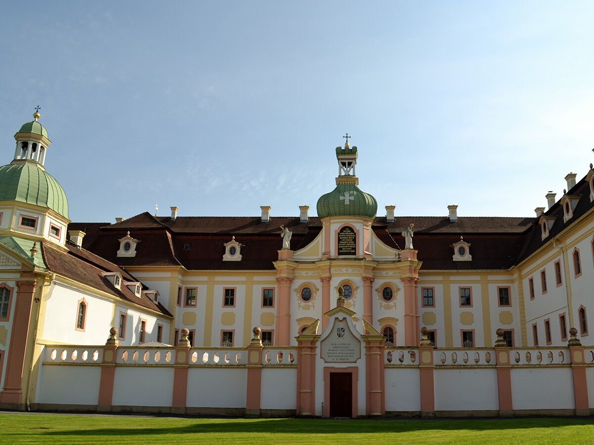 Stift Göttweig, Benediktinerabtei in Österreich, mit prunkvoller Barockfassade, grünen Kuppeln und rotem Dach unter blauem Himmel.