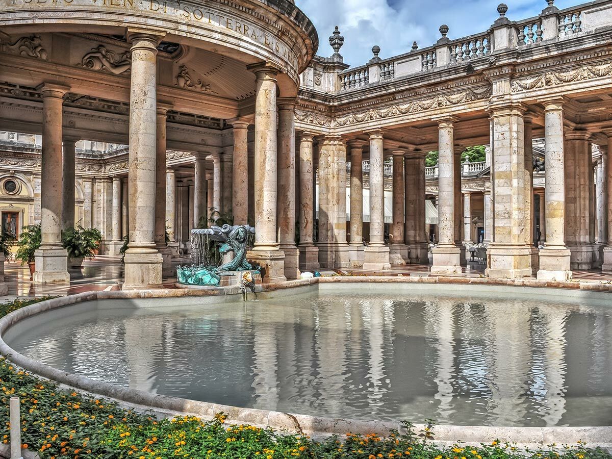 Blick auf den historischen italienischen Kurort Terme Tettuccio mit Säulen, Bogenarchitektur und Drachenbrunnen.