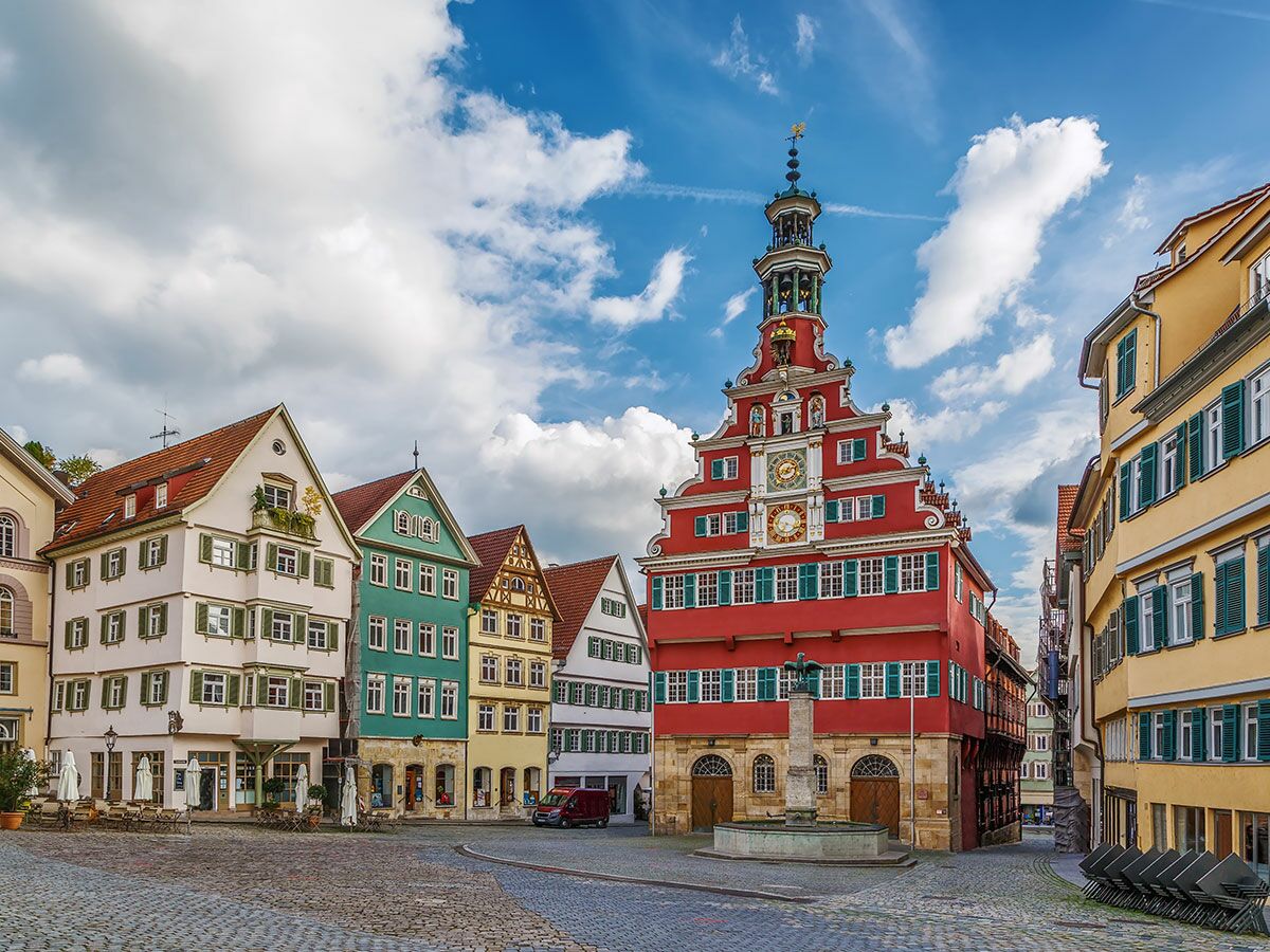 Der Marktplatz von Tübingen mit dem roten Rathaus, bunten Fachwerkhäusern, Brunnen und Kopfsteinpflaster unter blauem Himmel.