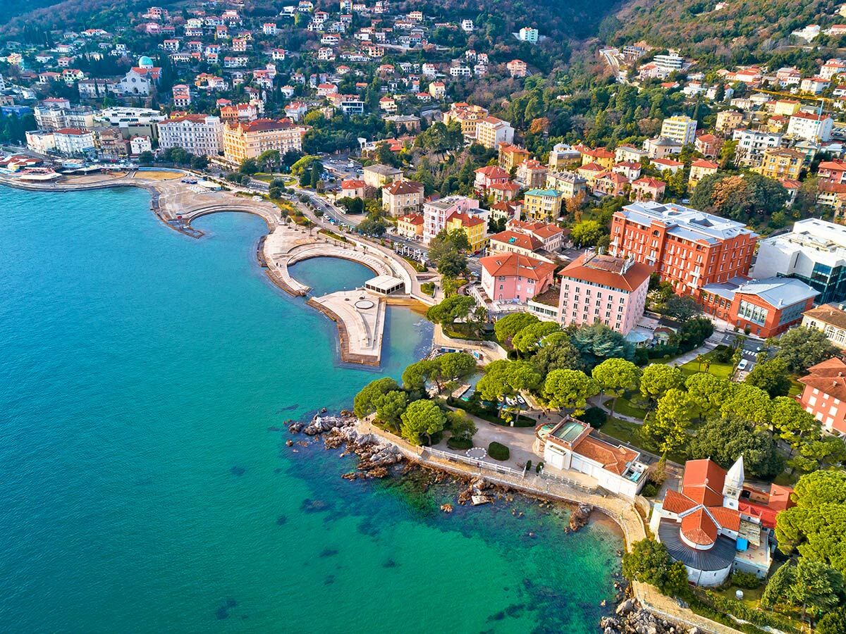 Luftbild der kroatischen Küstenstadt Opatija an der Adria, mit bunten Gebäuden, Promenade, Meer und grünen Hügeln.