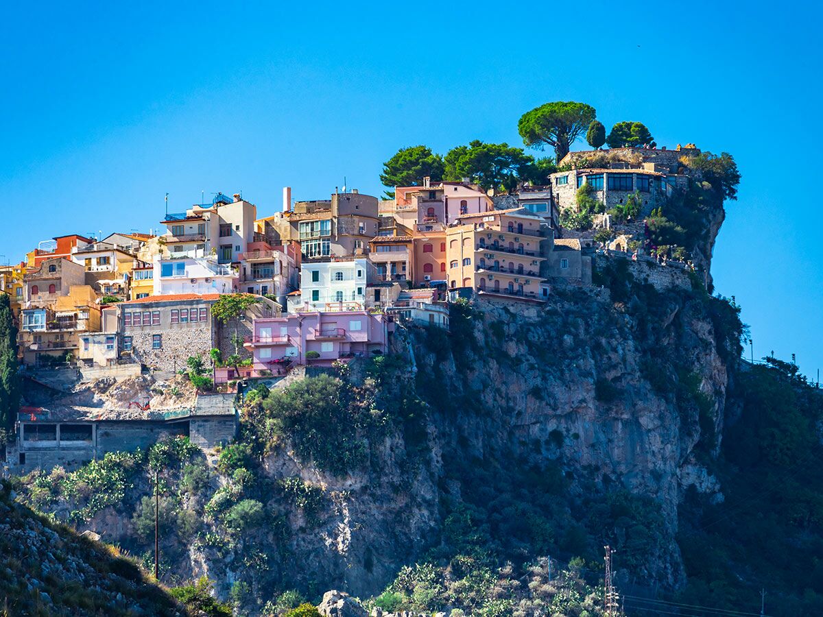 Malerische Küstenstadt mit bunten Häusern, die an einer steilen Felsklippe unter blauem Himmel gebaut sind, mediterranes Flair.