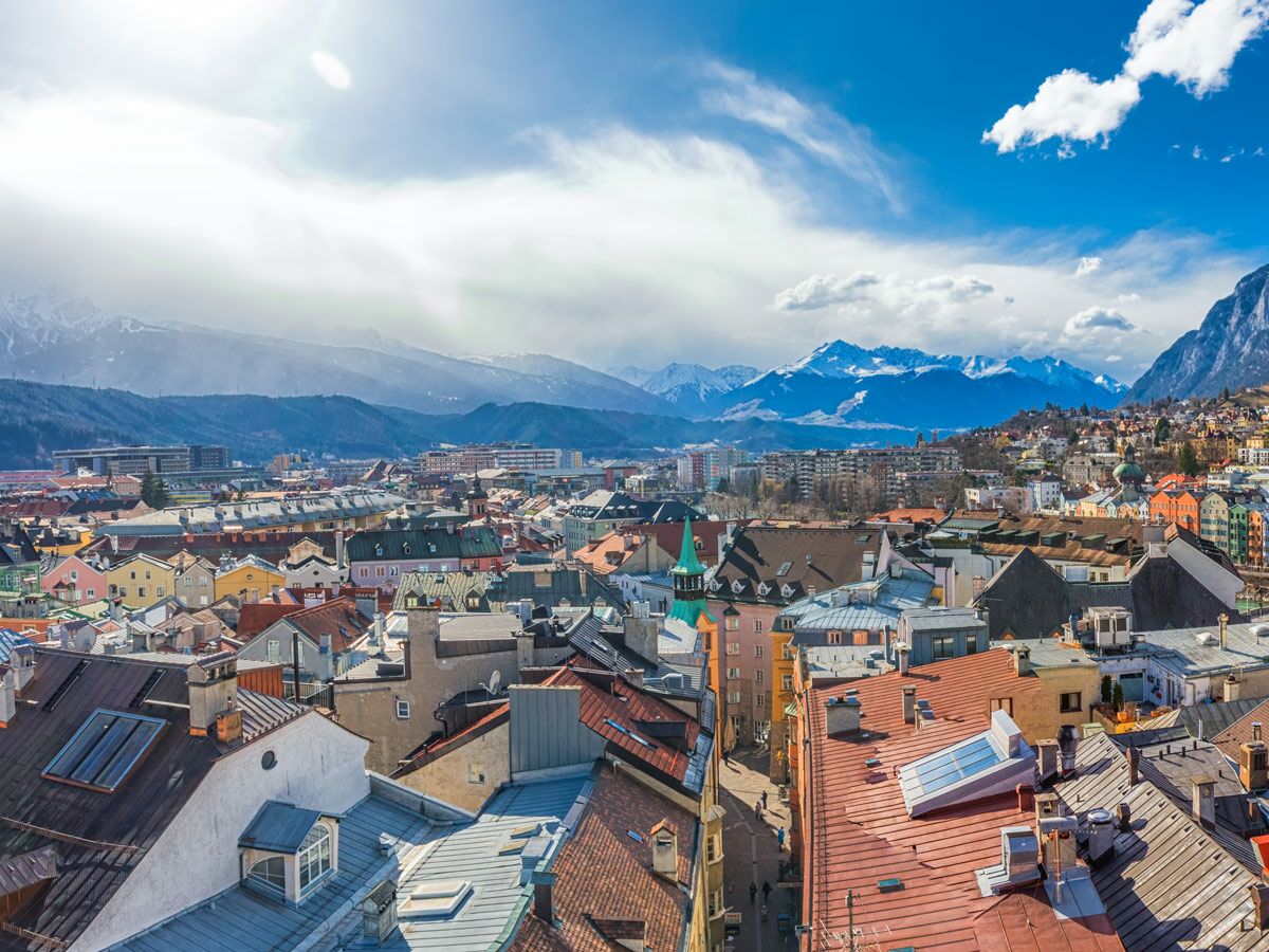 Luftbild von Innsbruck, Österreich, mit bunten Dächern, Altstadt und majestätischen, schneebedeckten Alpen im Hintergrund.