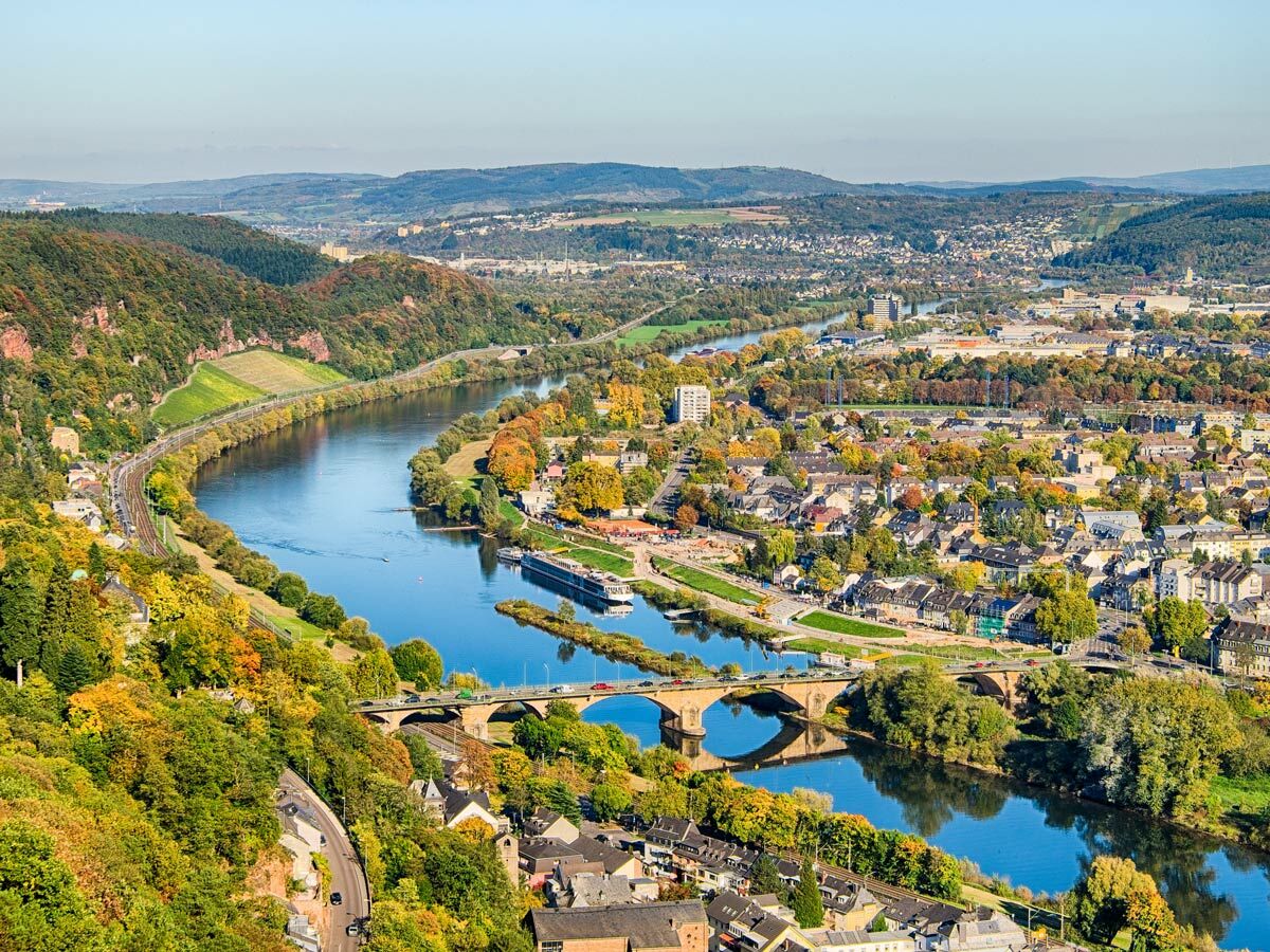 Luftaufnahme der deutschen Stadt Trier an der Mosel im Herbst mit historischer Brücke, Fluss und bunten Wäldern.