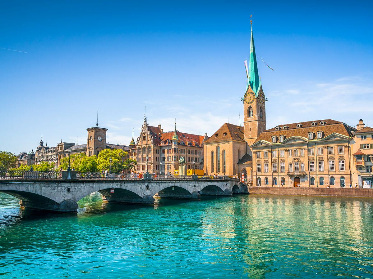 Zürich Panoramablick Limmat Fluss, Münsterbrücke, Fraumünsterkirche, historische Gebäude und blauer Himmel.