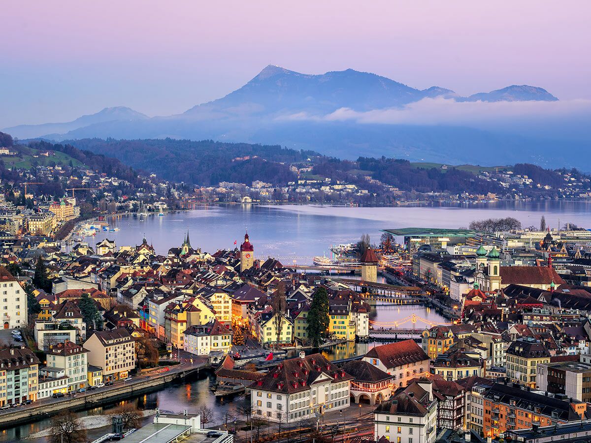 Panoramablick auf Luzern im Abendlicht mit Altstadt, Kapellbrücke, Vierwaldstättersee und Bergen.