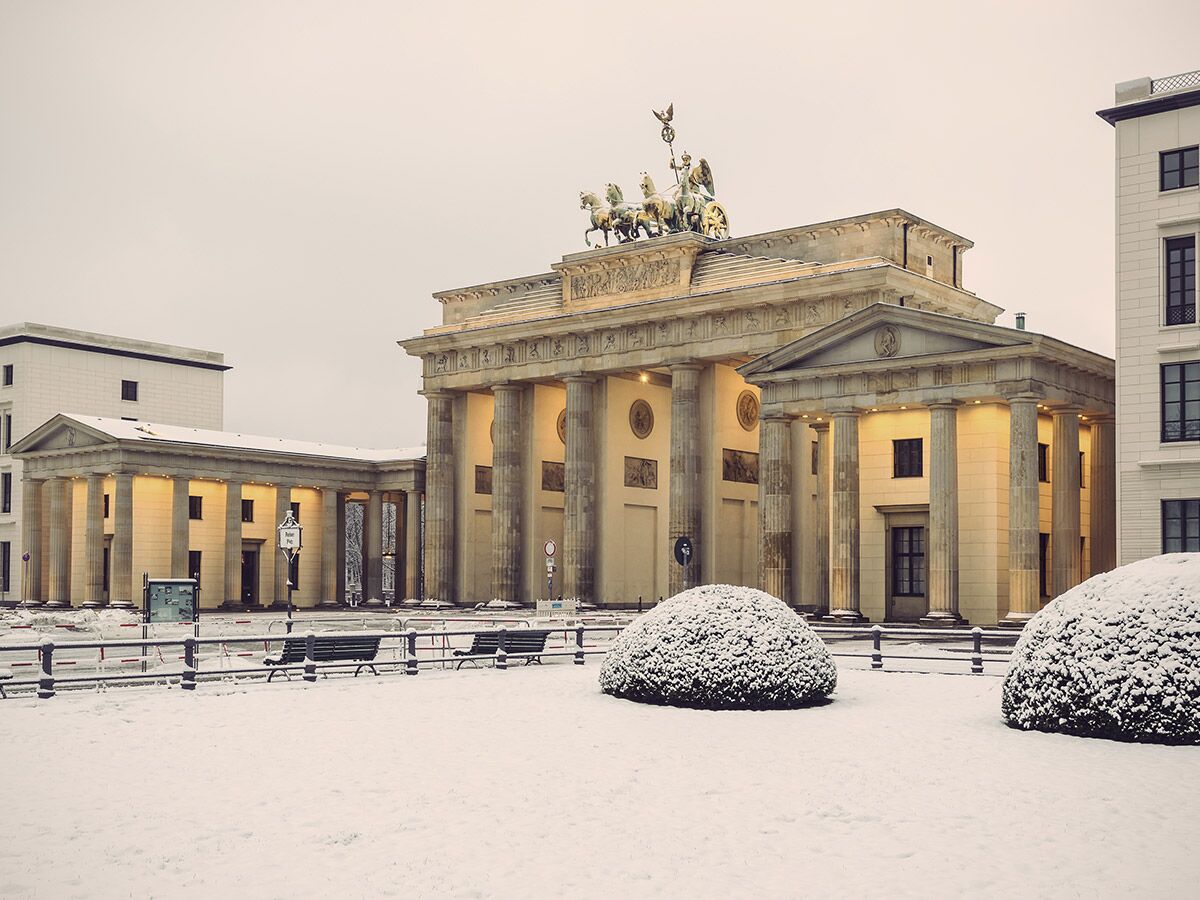 Brandenburger Tor, Berlin, Deutschland, im Schnee. Zeigt Quadriga, klassizistische Architektur und verschneite Parklandschaft.