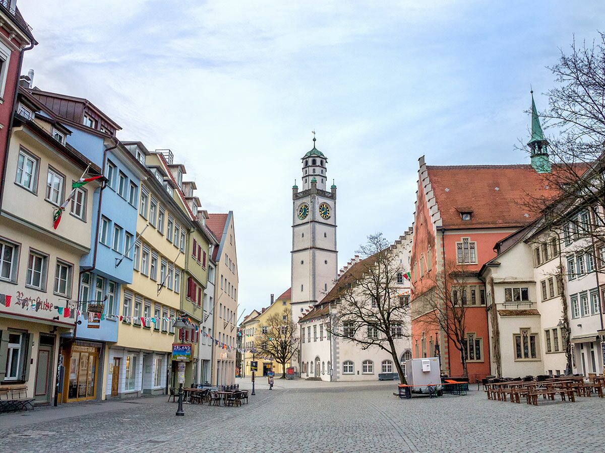 Blick auf den historischen Marktplatz von Ravensburg mit dem Rathaus-Glockenturm, bunten Häusern und Kopfsteinpflaster.