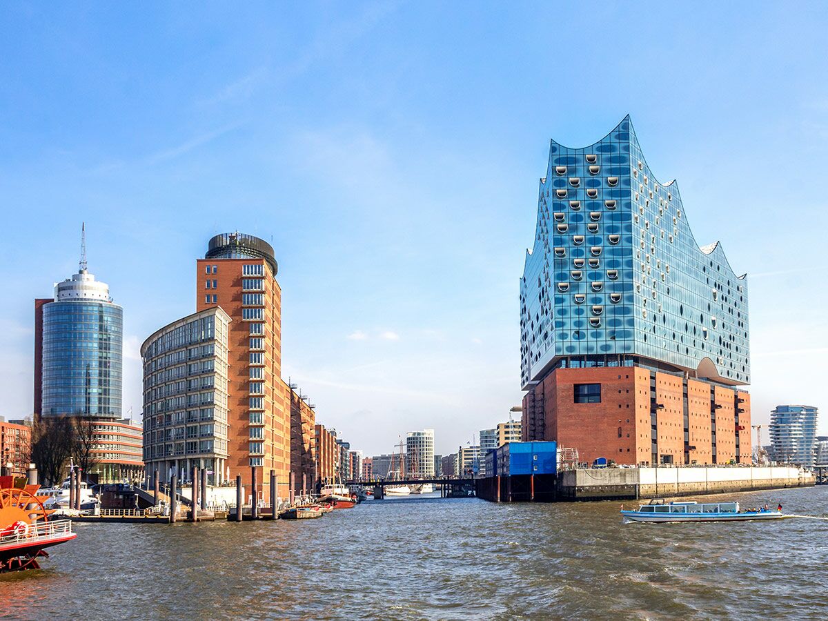 Die Elbphilharmonie und moderne Gebäude in Hamburgs HafenCity am Fluss Elbe unter blauem Himmel mit Booten.