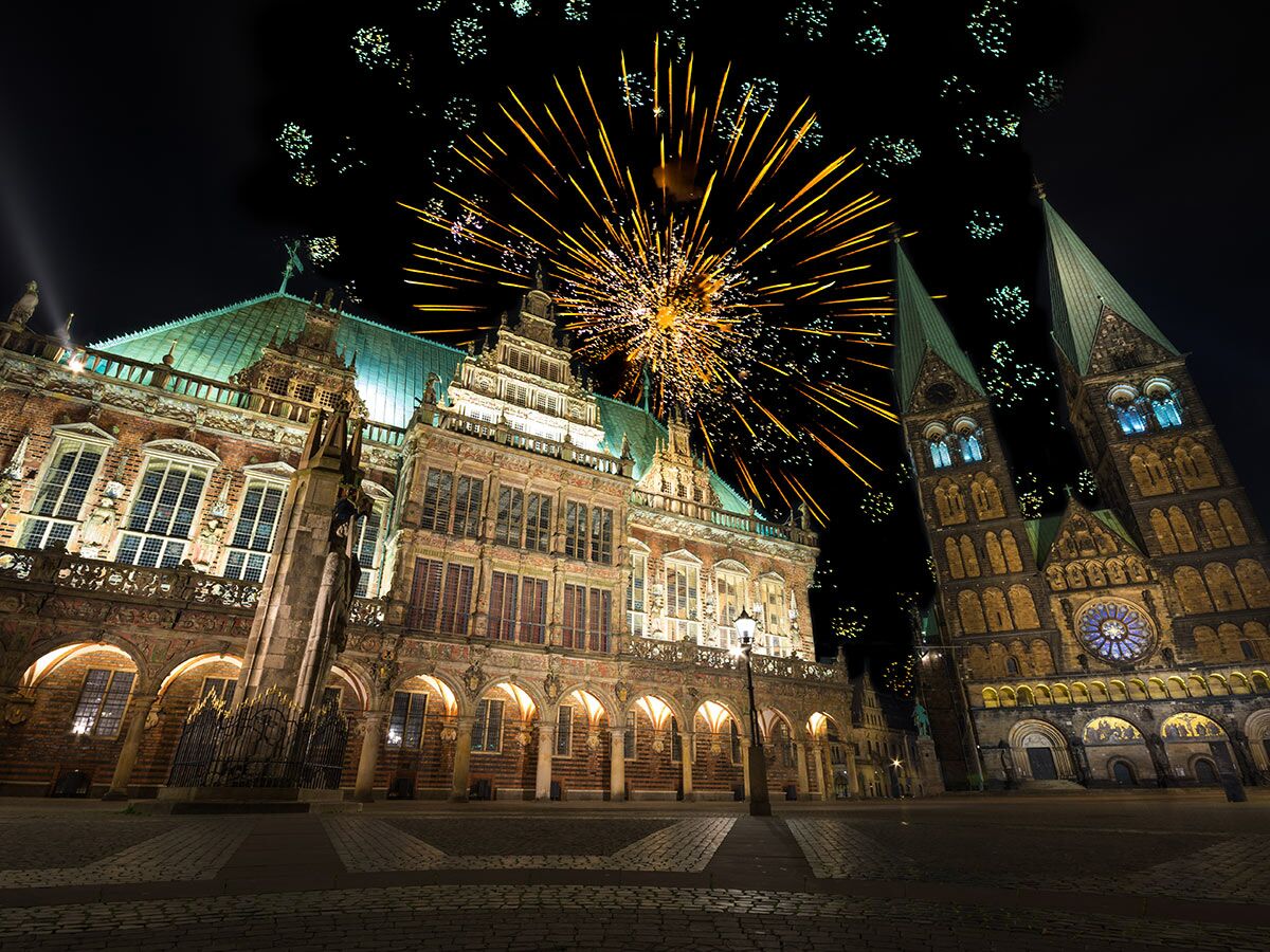 Historisches Bremer Rathaus und Dom mit Feuerwerk bei Nacht, beleuchteter Marktplatz, festliche Stimmung.