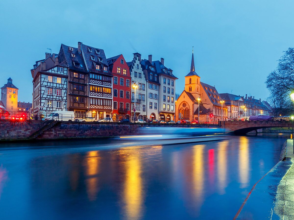 Malerische Altstadt von Strasbourg bei Nacht mit Fachwerkhäusern, Kirche und Fluss Spiegelungen.