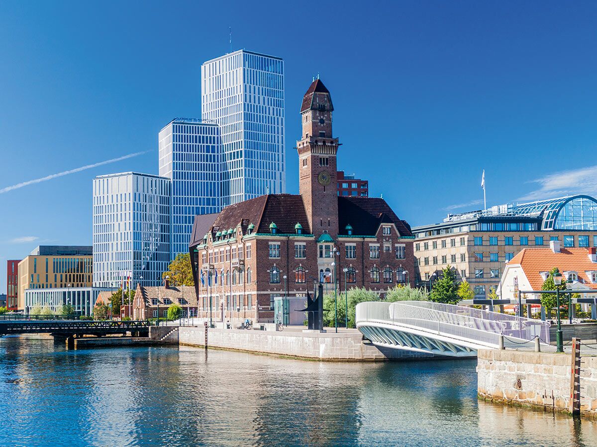 Malmö, Schweden: Stadtbild mit moderner Skyline aus Glashochhäusern, historischem Backsteingebäude mit Turm, Fluss und Brücken.