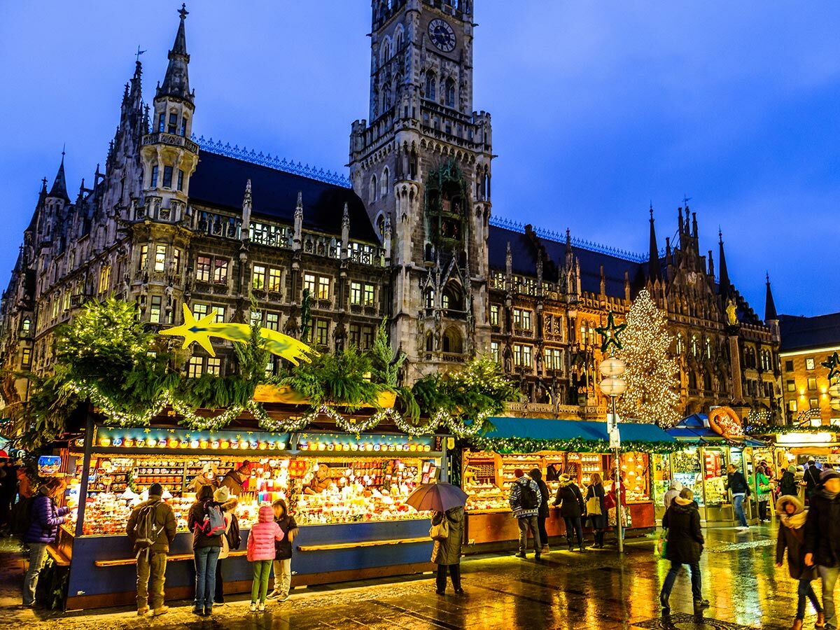 Weihnachtsmarkt am Neuen Rathaus München bei Abenddämmerung. Stände, Weihnachtsbaum, Lichterglanz und Menschen.
