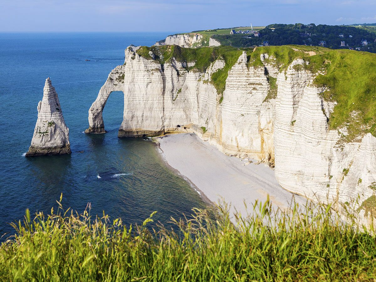 Spektakuläre Kreidefelsen von Étretat in der Normandie mit natürlichen Bögen, Felsnadel und Strand am blauen Meer.