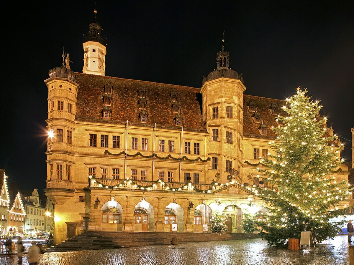 Rothenburg ob der Tauber Rathaus bei Nacht, festlich beleuchtet mit großem Weihnachtsbaum und Lichterketten.
