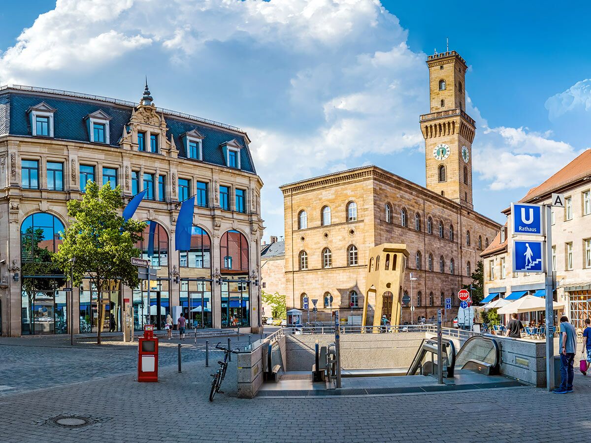 Blick auf das historische Rathaus und einen belebten Platz in Nürnberg mit U-Bahn-Eingang und Geschäften.