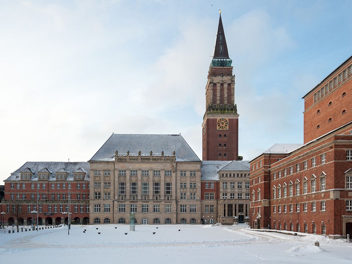 Blick auf das historische Rathaus Kiel mit seinem markanten Rathausturm, umgeben von schneebedecktem Platz an einem Wintertag.