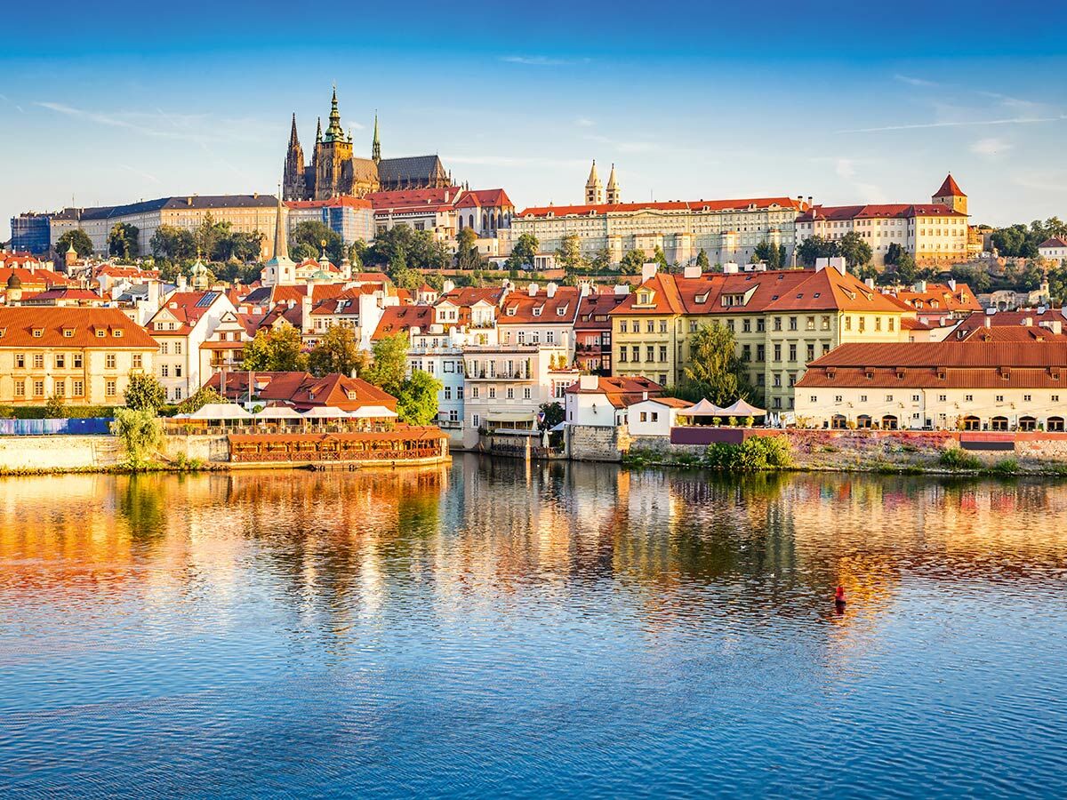 Panoramablick auf Prag mit der Moldau, historischen Gebäuden und dem majestätischen Prager Schloss mit St. Veits-Dom bei Tag.
