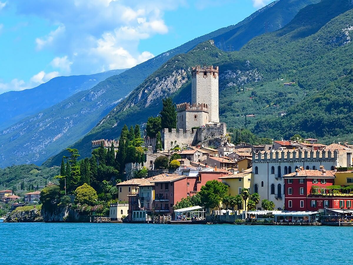 Blick auf Malcesine am Gardasee mit Scaliger Schloss, bunten Häusern und Bergen im Hintergrund. Idyllische italienische Landschaft.