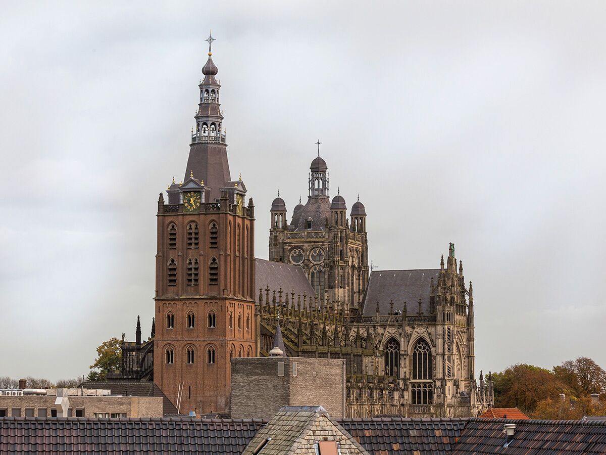 St. Johannes Kathedrale 's-Hertogenbosch mit hohem Backsteinturm und gotischen Details unter bewölktem Himmel.