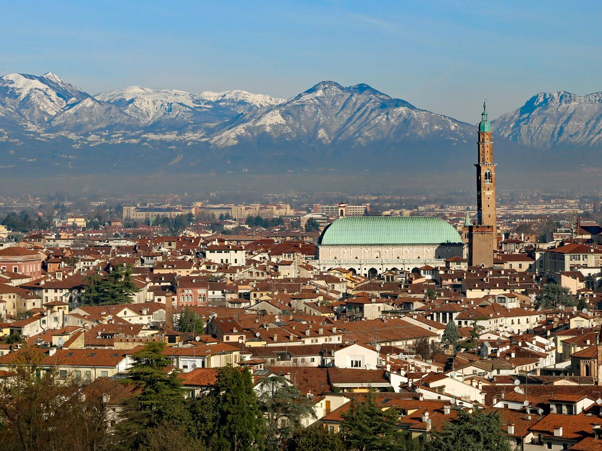 Panoramablick auf Vicenza, Italien, mit roten Dächern, Basilika Palladiana, Torre Bissara und schneebedeckten Alpen.