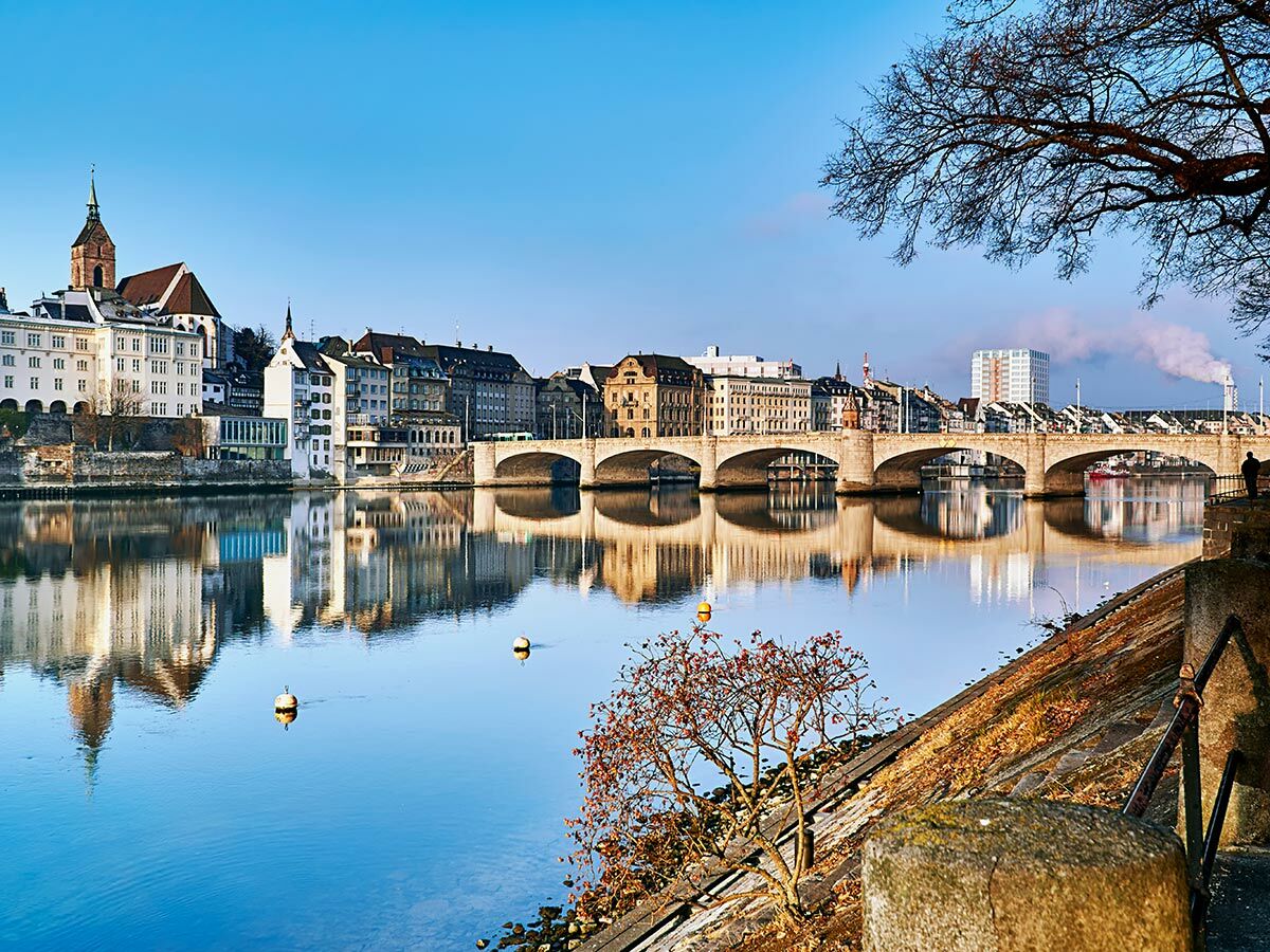 Panoramablick auf Basel mit Rhein, Mittlerer Brücke, Münster und alter Stadt bei Wintersonne. Blaue Reflexionen im Fluss.