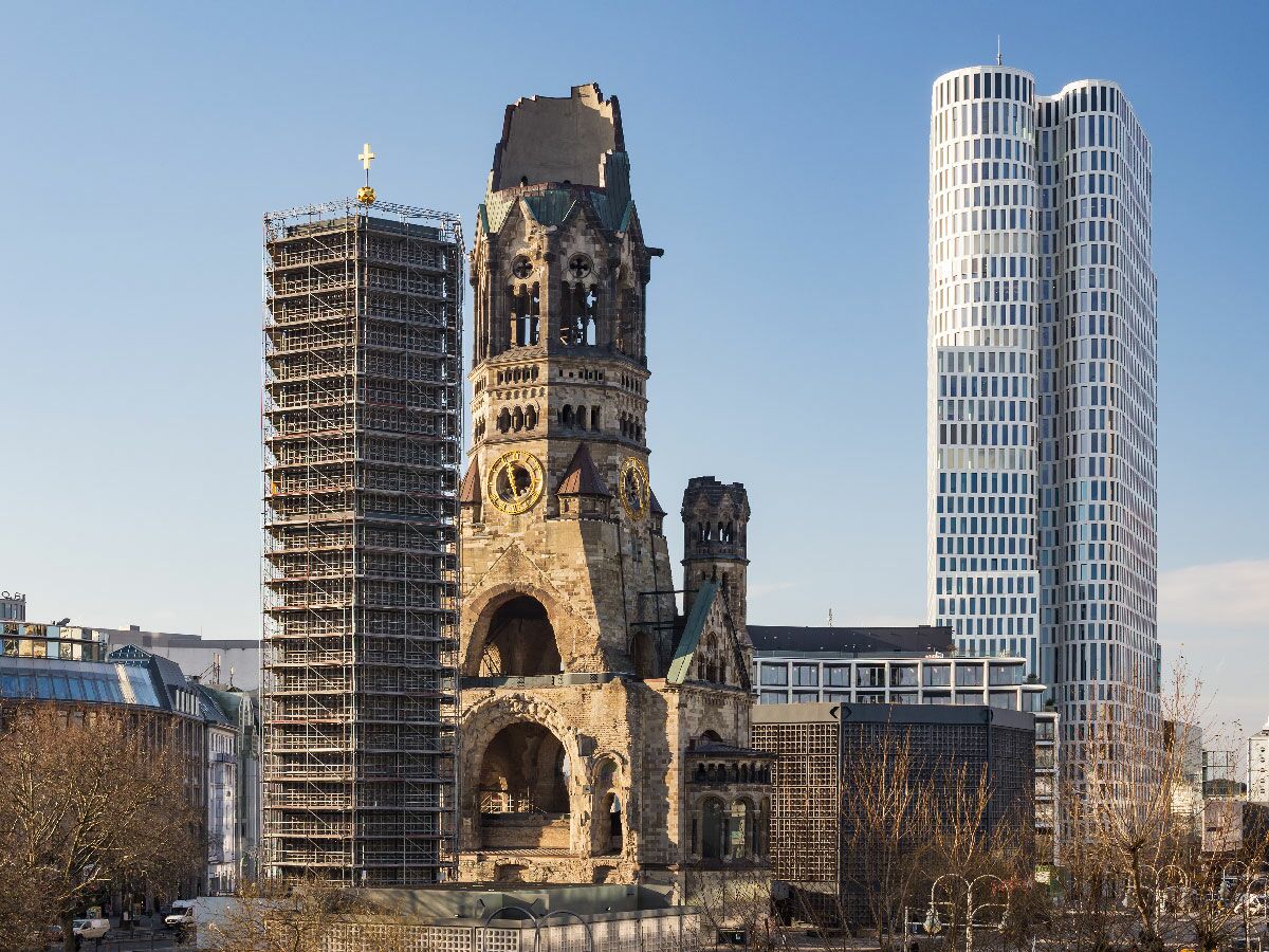 Die Kaiser-Wilhelm-Gedächtniskirche, eine Ruine mit Neubauten, umgeben von modernen Wolkenkratzern in Berlin.