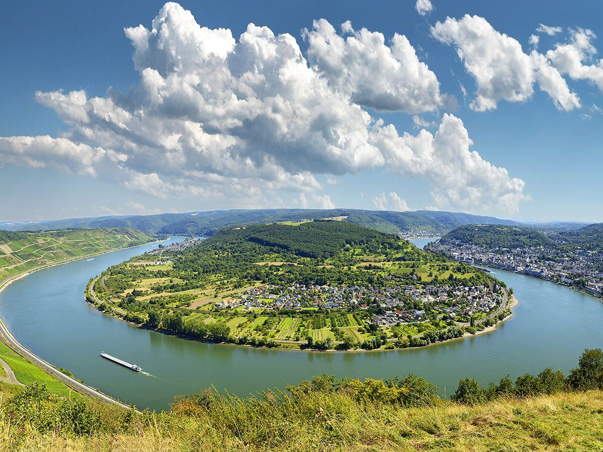 Panoramablick auf die Saarschleife, einen Flussmäander umgeben von grünen Wäldern, Weinbergen und Orten unter blauem Himmel.