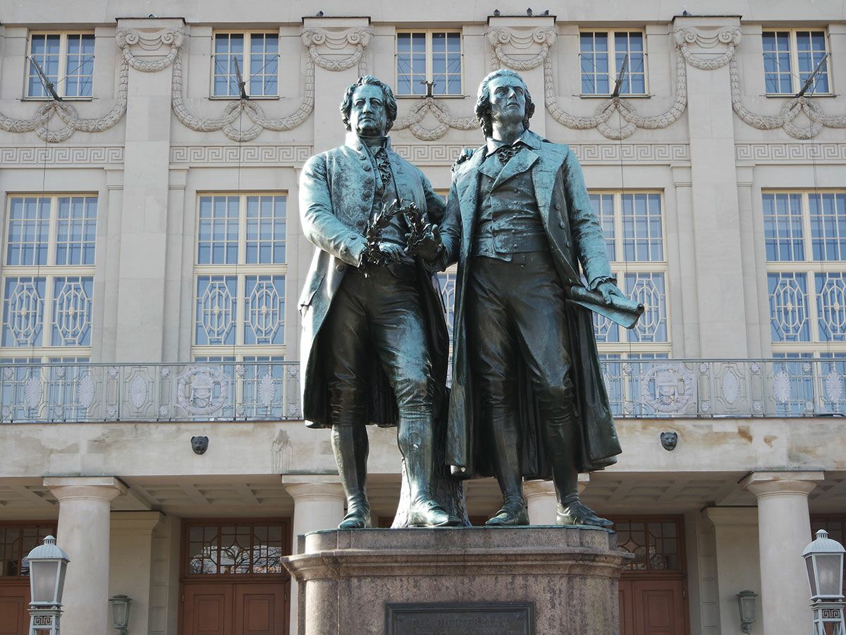 Goethe-Schiller-Denkmal in Weimar: Zwei bronzene Statuen der deutschen Dichter vor einem historischen Gebäude.
