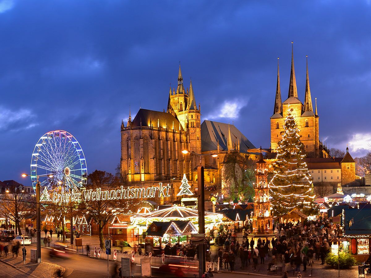 Erfurter Weihnachtsmarkt mit beleuchtetem Dom, Severikirche, Riesenrad und Weihnachtsbaum in der Abenddämmerung und vielen Besuchern.