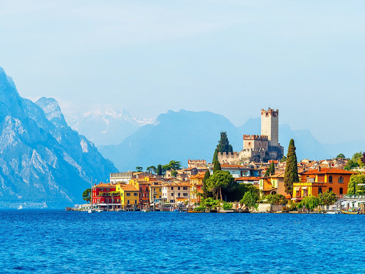 Malerisches Malcesine am Gardasee mit Scaligerburg, farbenfrohen Häusern, blauem Wasser und majestätischen Bergen im Hintergrund.