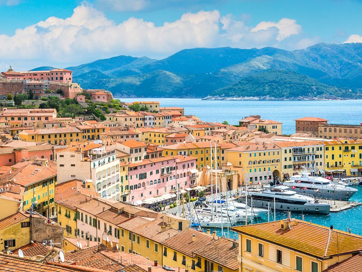 Panoramablick auf Portoferraio, Elba mit seinem malerischen Hafen voller Yachten, bunten Häusern und einer historischen Festung im Hintergrund.