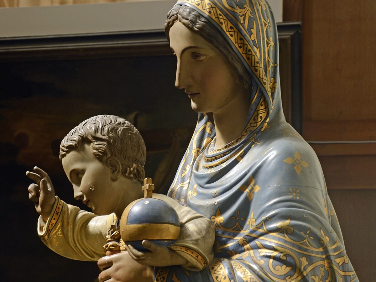 Bemalte Statue von Maria und dem Jesuskind, das eine Weltkugel hält, in blau-goldener Robe.