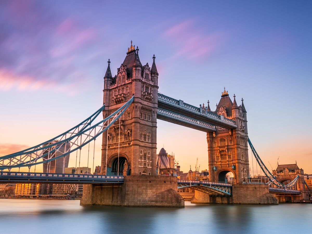Majestätische Tower Bridge in London bei Sonnenuntergang über der Themse, mit pink-orange Himmel und Stadtsilhouette.