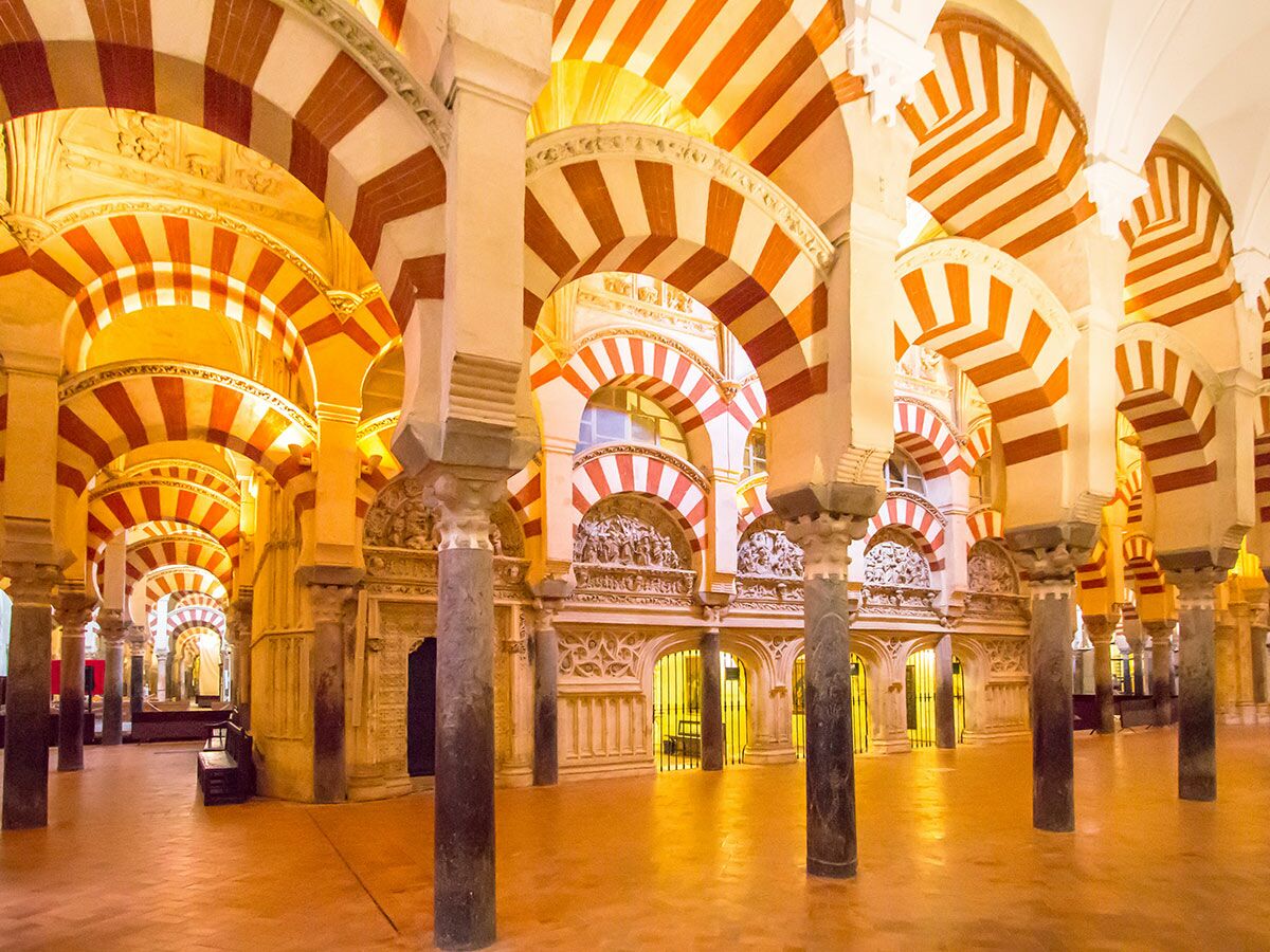 Innenansicht der Mezquita-Kathedrale von Córdoba mit charakteristischen rot-weiß gestreiften Hufeisenbögen und Säulenreihen.