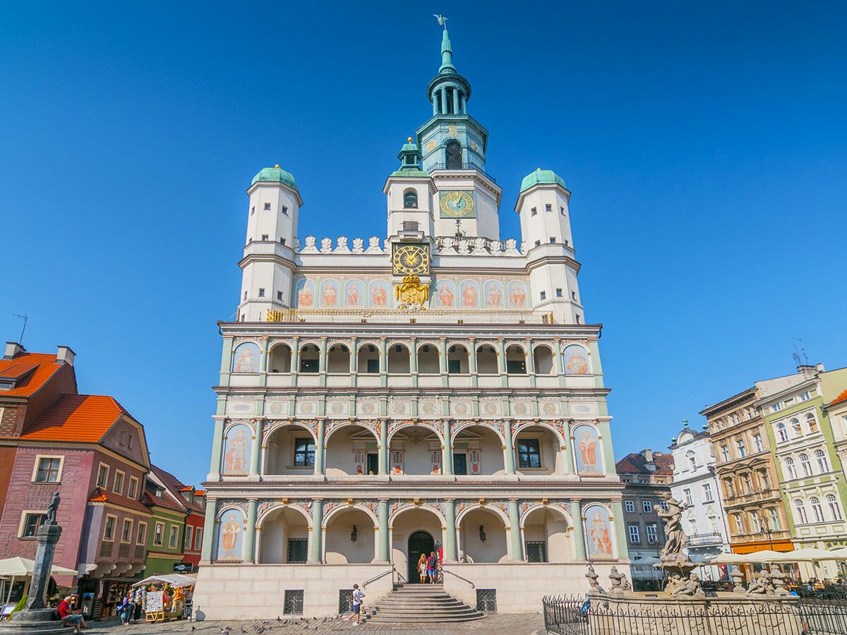 Historisches Rathaus Posen am Alten Markt, Polen, mit Turm, bunter Fassade und Menschen unter blauem Himmel.