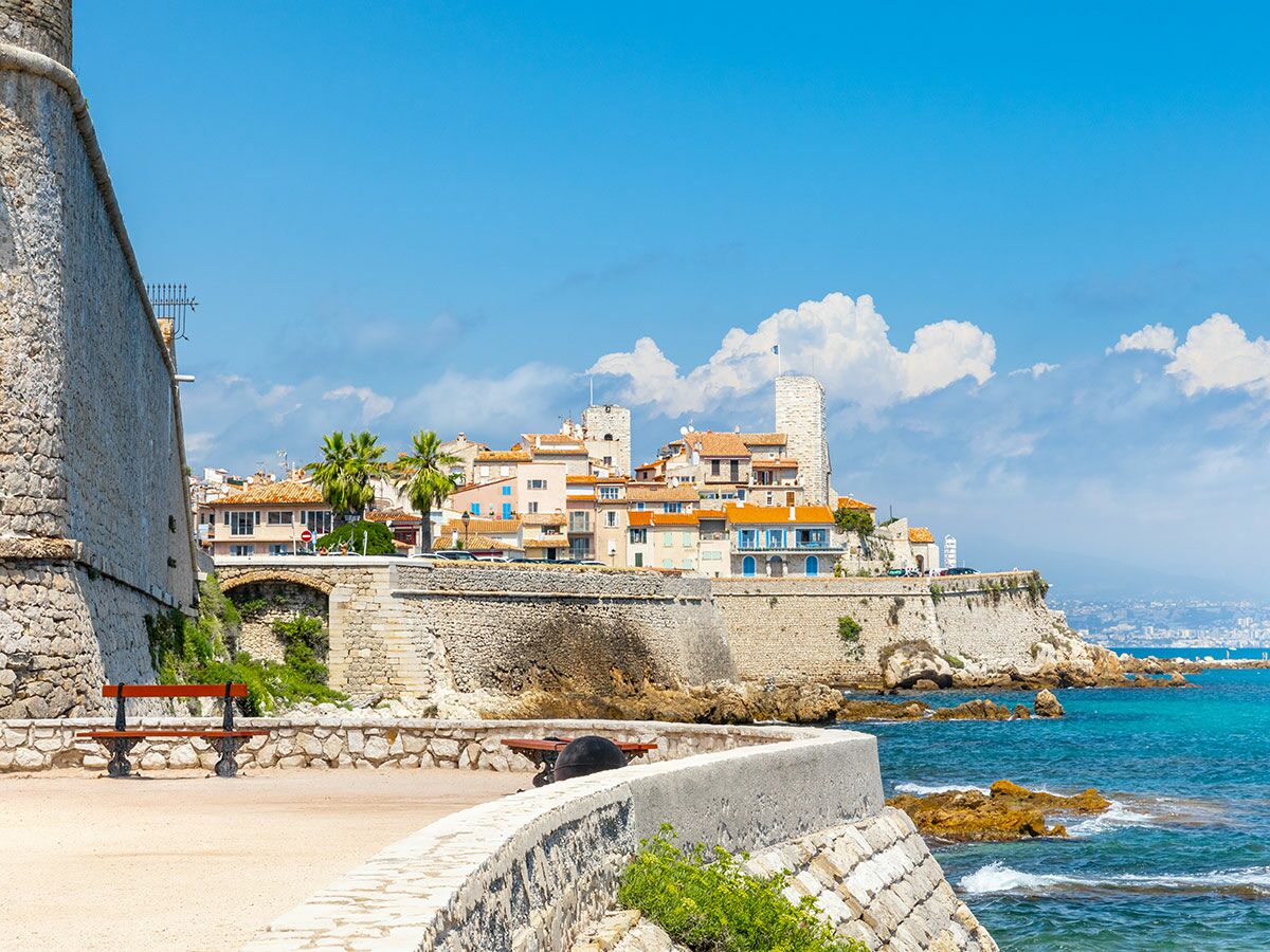 Blick auf die historische Altstadt von Antibes an der französischen Mittelmeerküste mit alten Stadtmauern, bunten Häusern und blauem Meer bei Sonnenschein.
