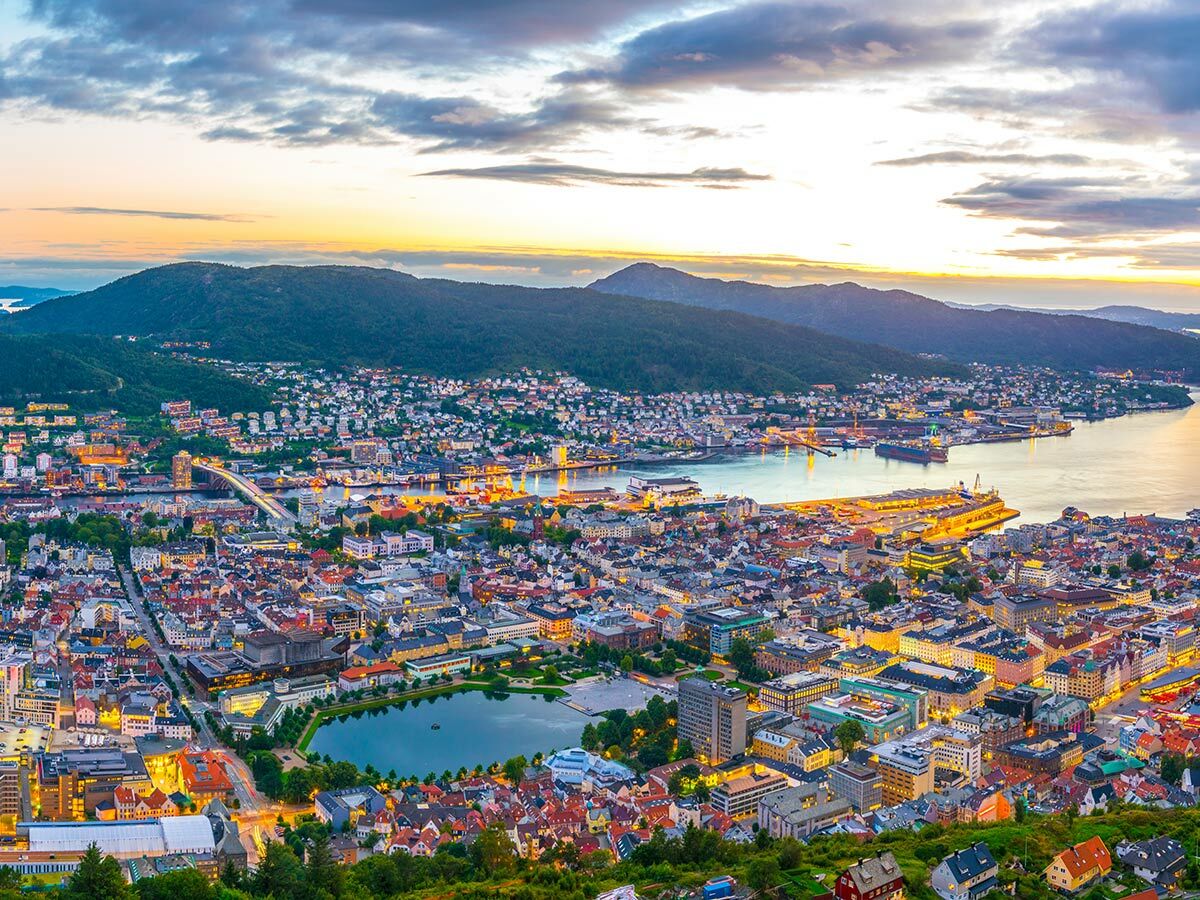 Bergen, Norwegen, bei Sonnenuntergang mit beleuchteter Stadt, Hafen, Bergen und See. Panoramablick über die Küstenstadt.