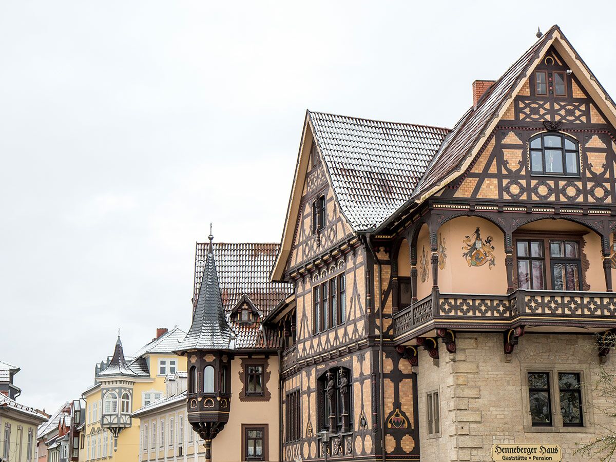Reihe historischer Fachwerkhäuser mit verschneiten Dächern und Verzierungen, darunter das Henneberger Haus, in einer deutschen Altstadt.