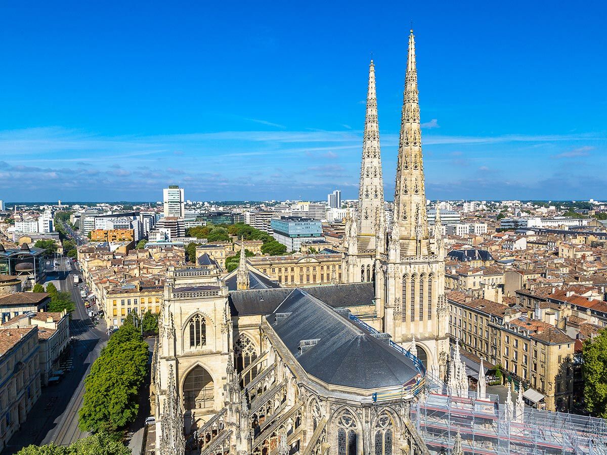 Luftaufnahme der gotischen Kathedrale Saint-André in Bordeaux, Frankreich, mit ihren zwei Türmen und der historischen Altstadt unter blauem Himmel.