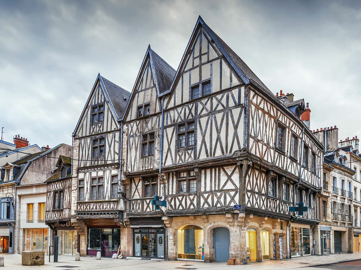Historische Fachwerkhäuser in der Altstadt von Orléans, Frankreich, mit markanten Fachwerkfassaden unter bewölktem Himmel.