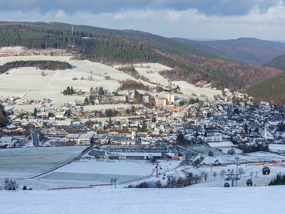 Panoramablick auf einen verschneiten Skiort mit Häusern, Pisten, Liften und Wäldern im winterlichen Harz, Deutschland.