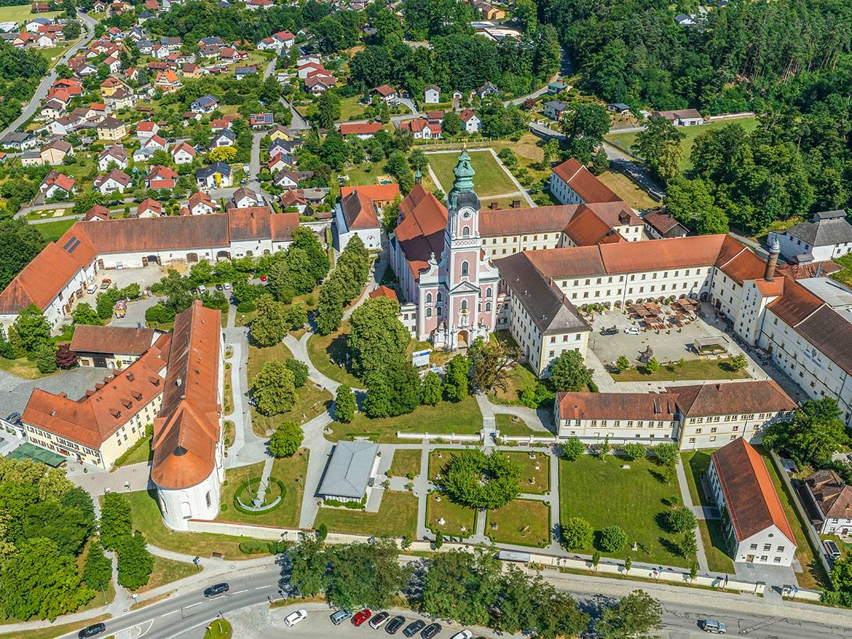 Luftaufnahme des Klosters Metten in Bayern mit seiner Barockkirche, Gebäuden, Innenhöfen und dem umliegenden Dorf.