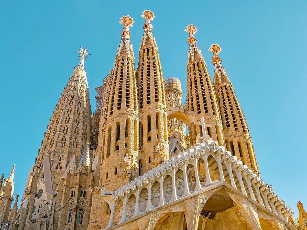 Majestätische Ansicht der Sagrada Familia in Barcelona mit ihren hohen Türmen und detaillierten Fassaden unter blauem Himmel.