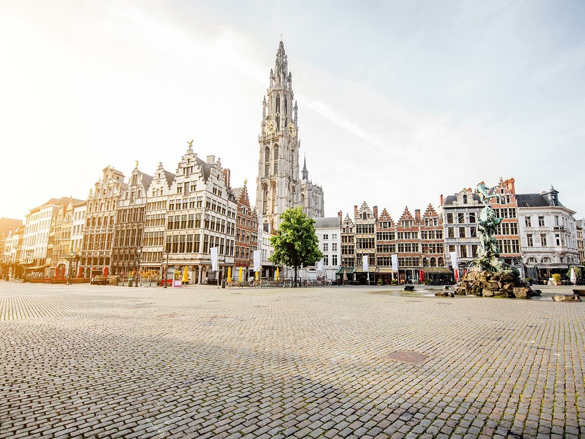 Der Grote Markt in Antwerpen mit der Kathedrale und historischen Zunfthäusern bei hellem Sonnenlicht am Morgen.