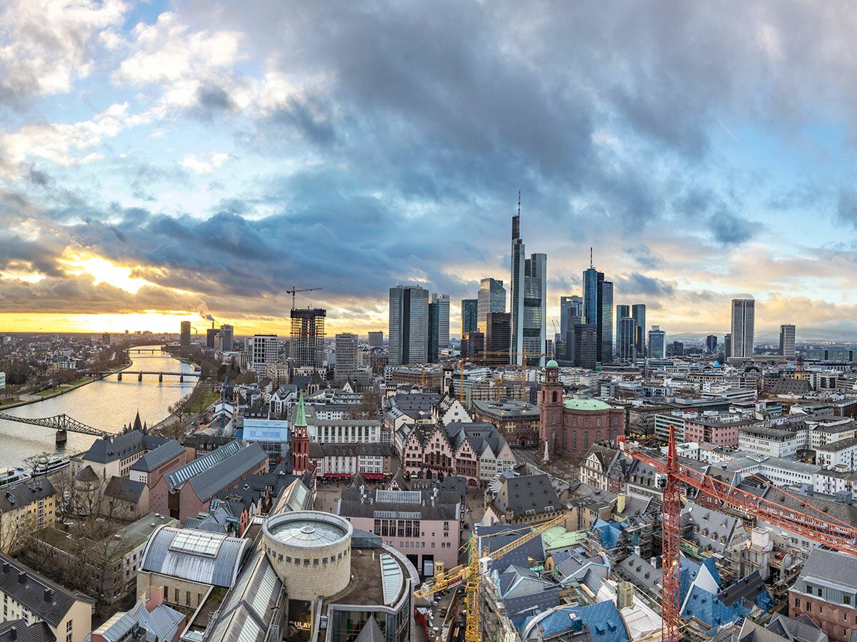 Panoramablick auf die Frankfurter Skyline bei Sonnenuntergang, mit Hochhäusern, dem Main Fluss und der historischen Altstadt.