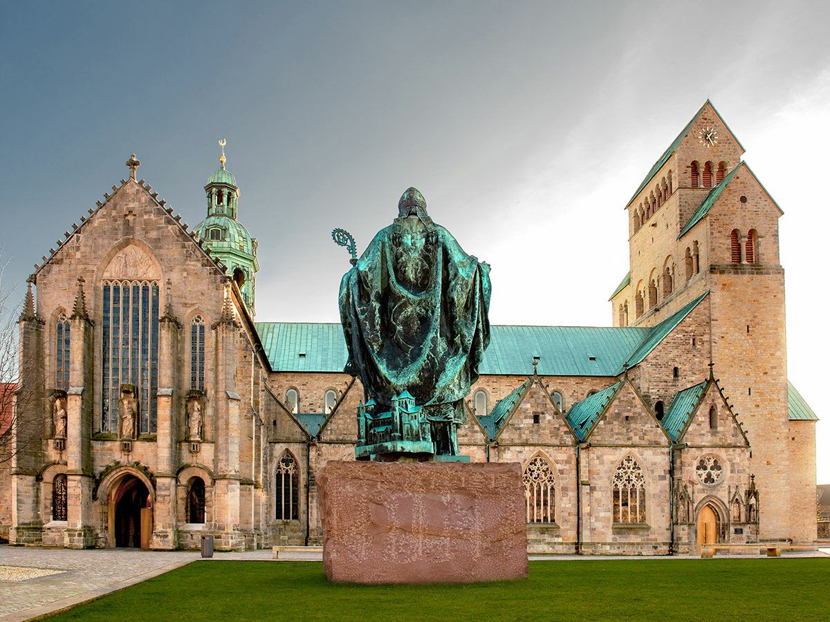 Blick auf den Hildesheimer Dom, UNESCO-Weltkulturerbe, mit der Bronzestatue des Heiligen Bernward im Vordergrund.