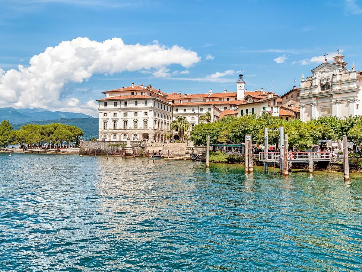 Blick vom Lago Maggiore auf Isola Bella mit Borromäischem Palast, Kirche und Dorf unter blauem Himmel.